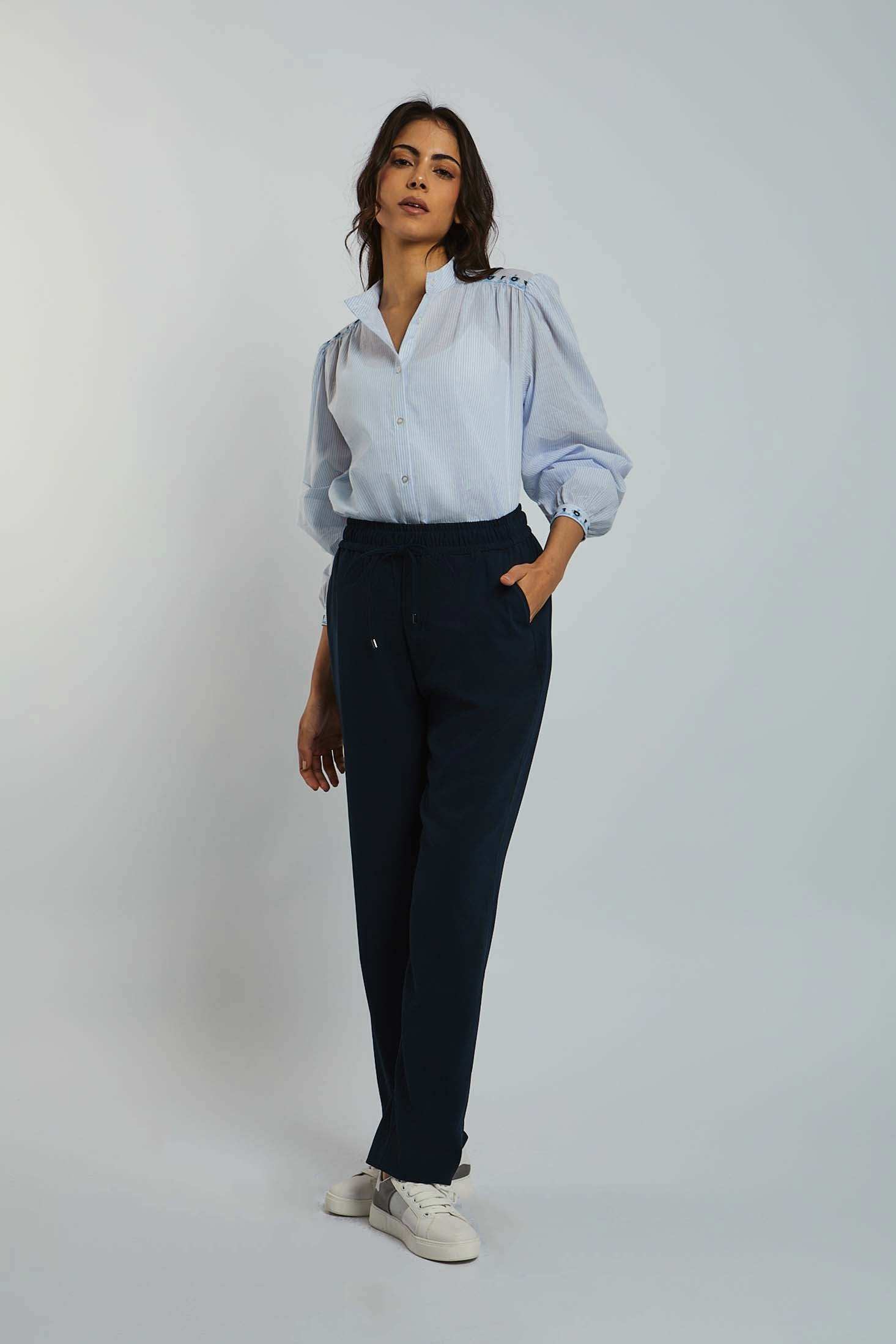 Woman wearing light blue button-up blouse with puff sleeves and navy casual pants