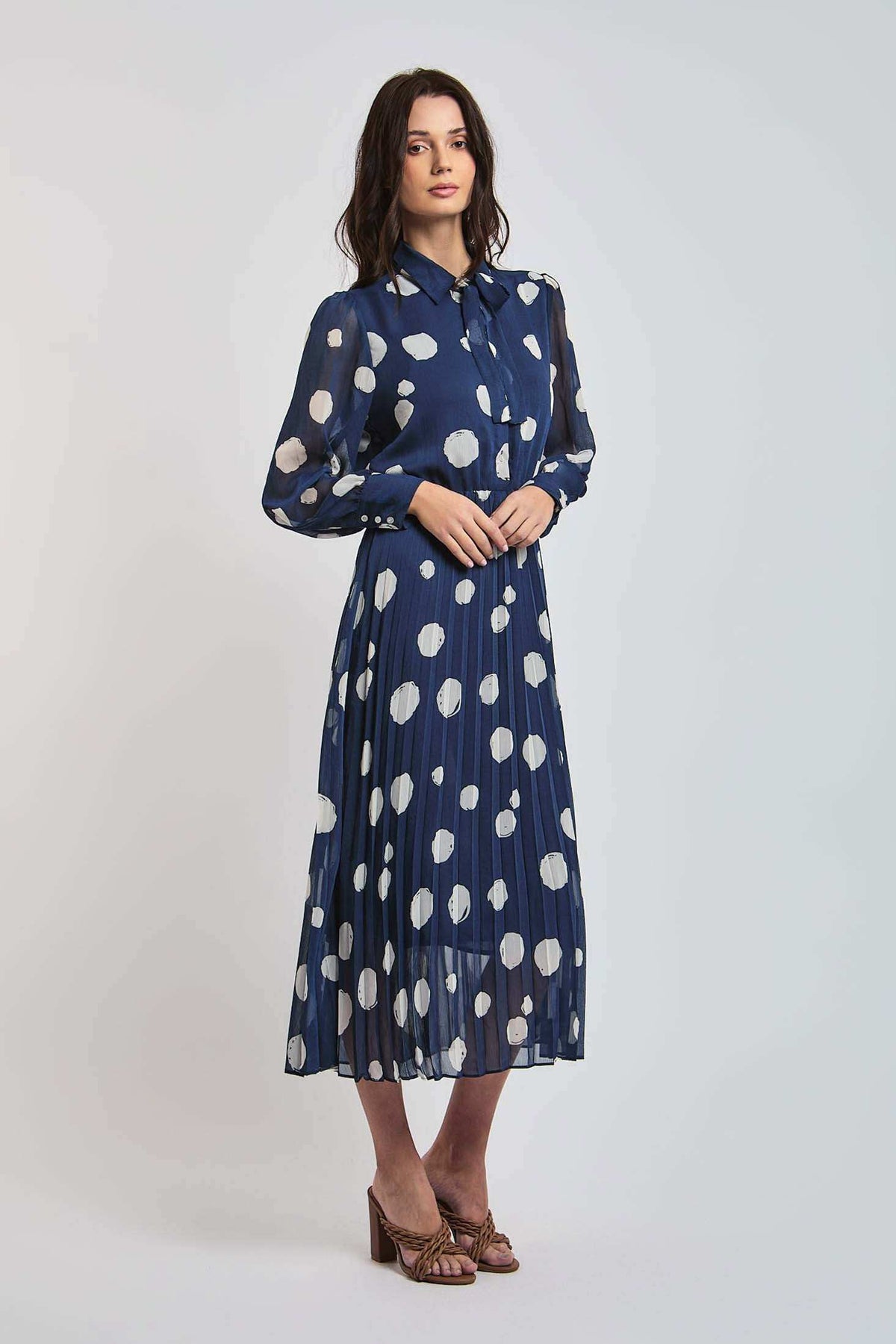 Woman wearing Dalydress navy blue polka dot midi dress with long sleeves and pleated skirt