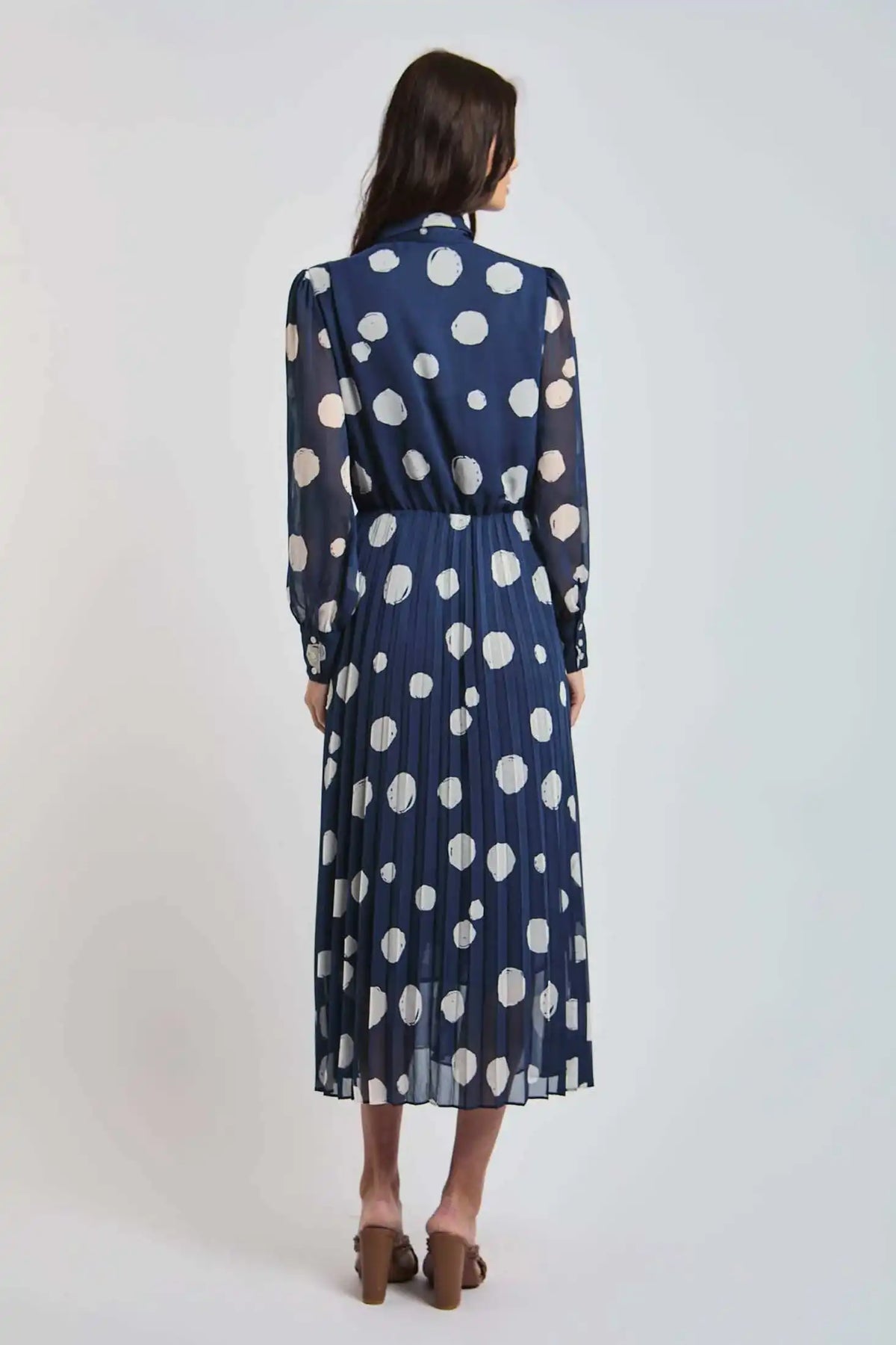Woman wearing navy blue polka dot pleated midi dress from Dalydress, back view