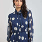 Woman wearing a Dalydress blue polka dot pleated dress with tie-neck detail
