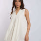 Woman modeling sleeveless white V-neck top with flowy design, paired with brown pants