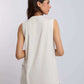 Woman wearing sleeveless ivory top with brown pants, photographed from the back
