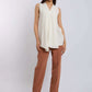 Woman wearing sleeveless cream tunic top and brown straight-leg trousers, standing indoors