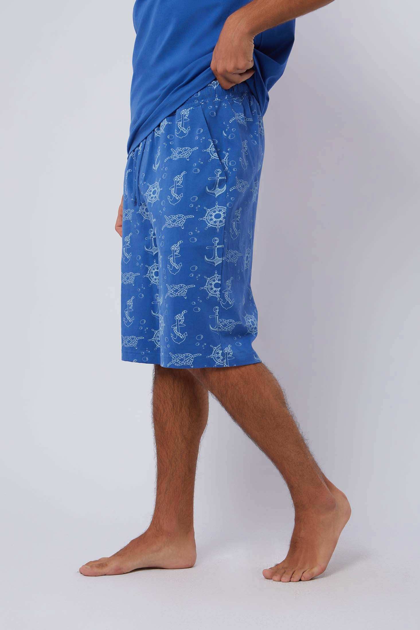 Man wearing blue Dalydress shorts with nautical anchor and wheel print, side view