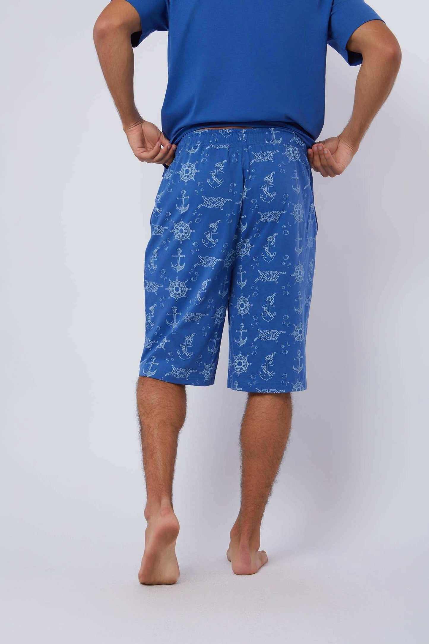 Man wearing blue Dalydress shorts with nautical anchor and wheel print, photographed from behind