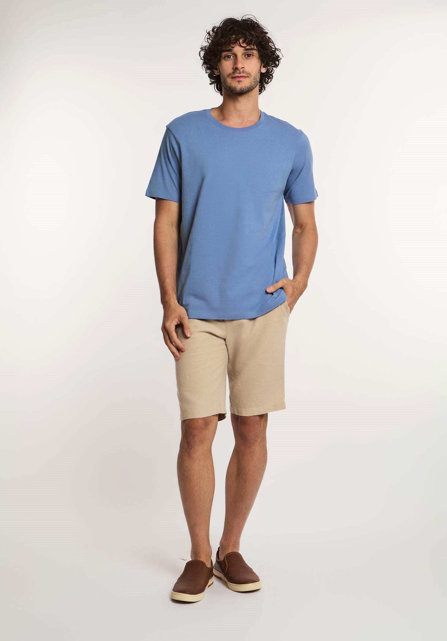 Man modeling Dalydress casual outfit with blue t-shirt and beige shorts on white background