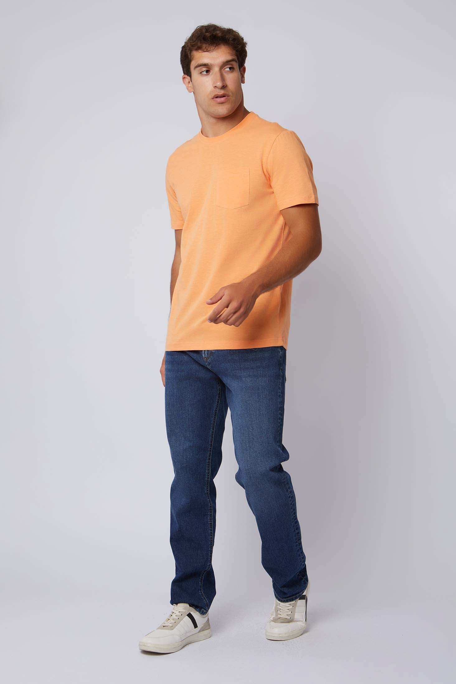 Man modeling Dalydress casual orange t-shirt with jeans and sneakers on plain background
