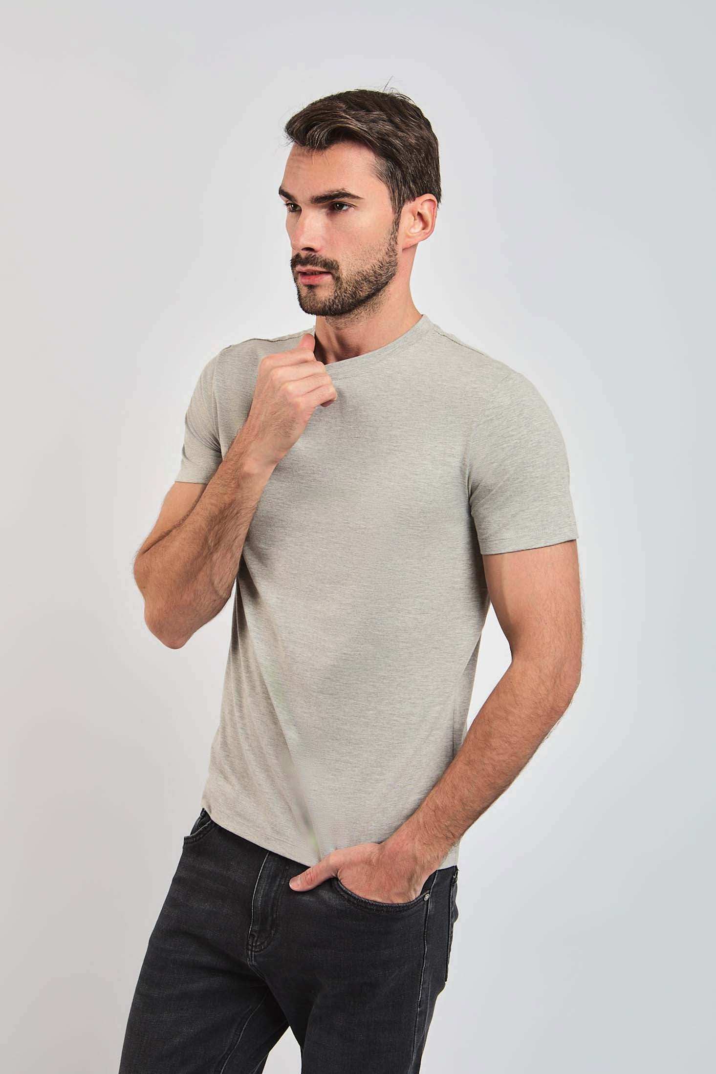 Male model in a light grey short-sleeve Dalydress t-shirt and black jeans against plain background