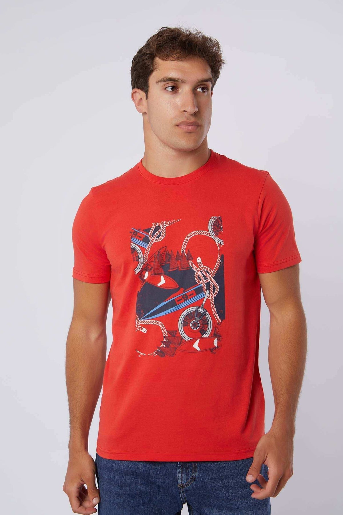 Man wearing Dalydress red graphic t-shirt with nautical print and blue jeans