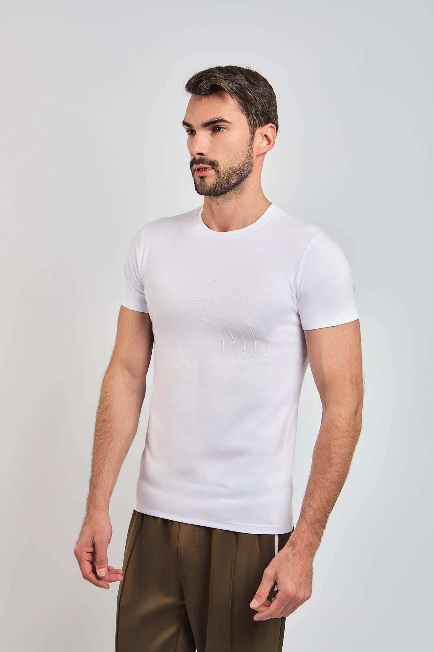 Man wearing fitted white short sleeve t-shirt with subtle circular design, brown pants