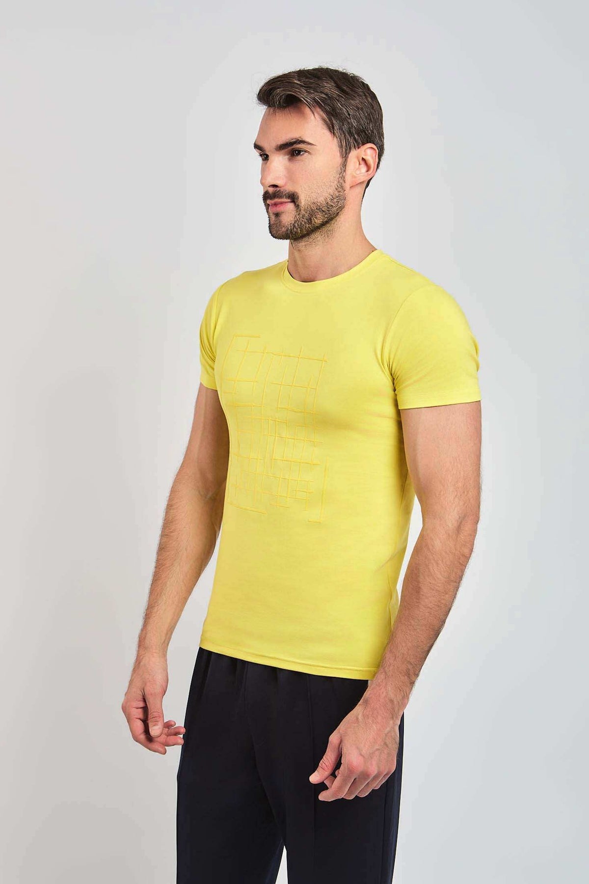 Man wearing slim fit yellow t-shirt with subtle geometric print and black pants