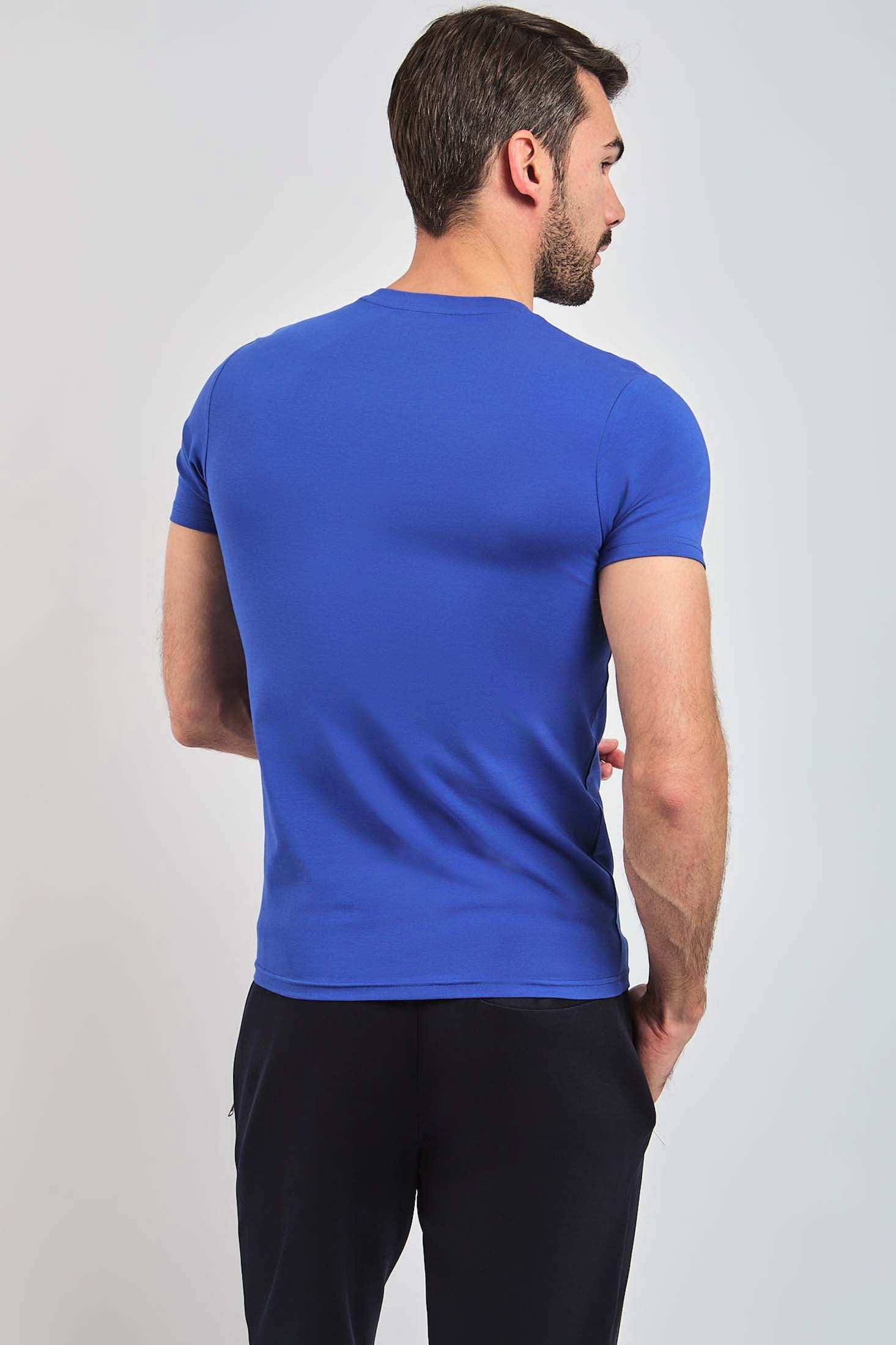 Man wearing fitted blue short sleeve t-shirt and black pants, back view, casual fashion