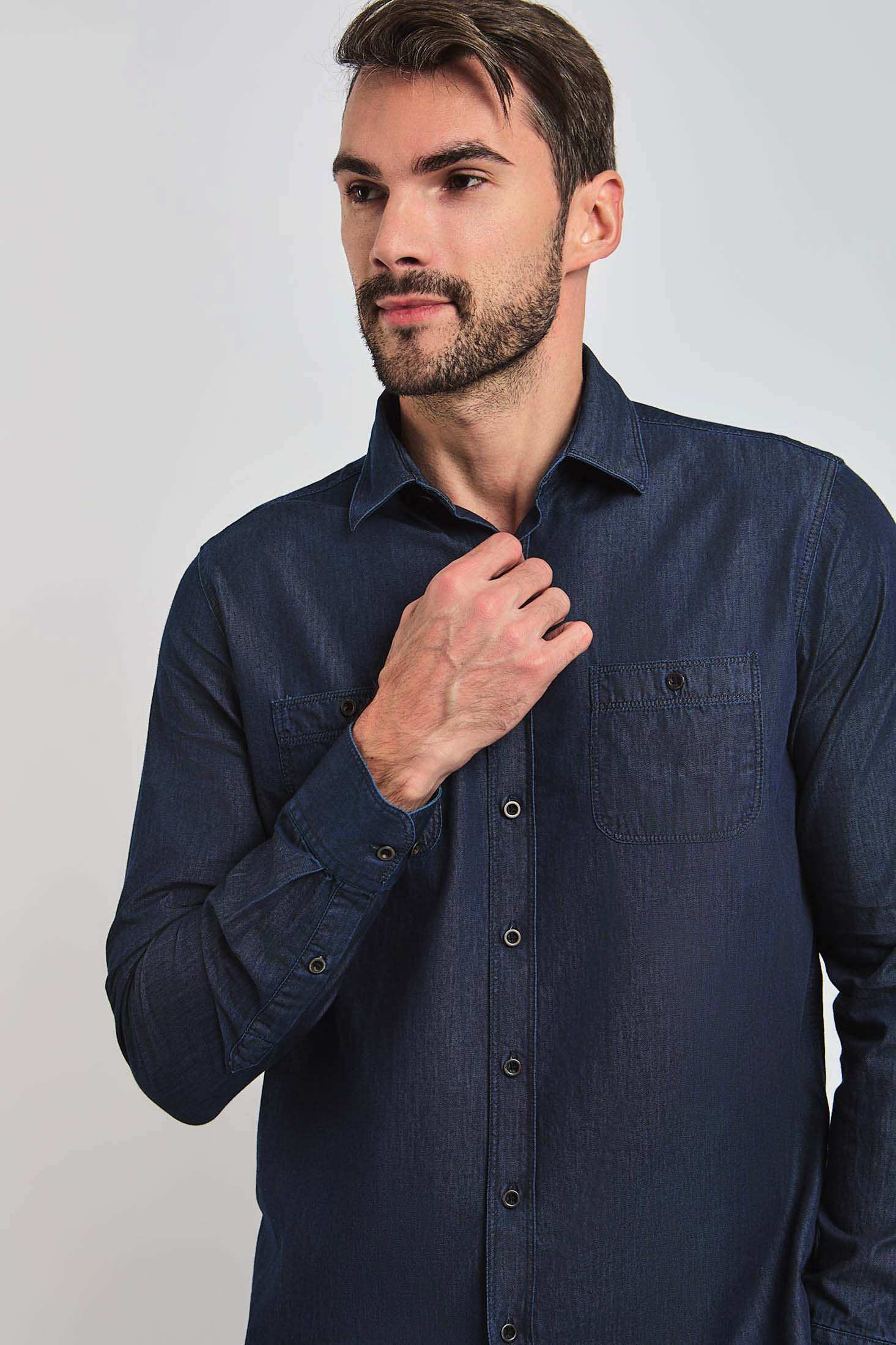 Man wearing a dark denim button-up shirt with chest pockets, casual men's fashion