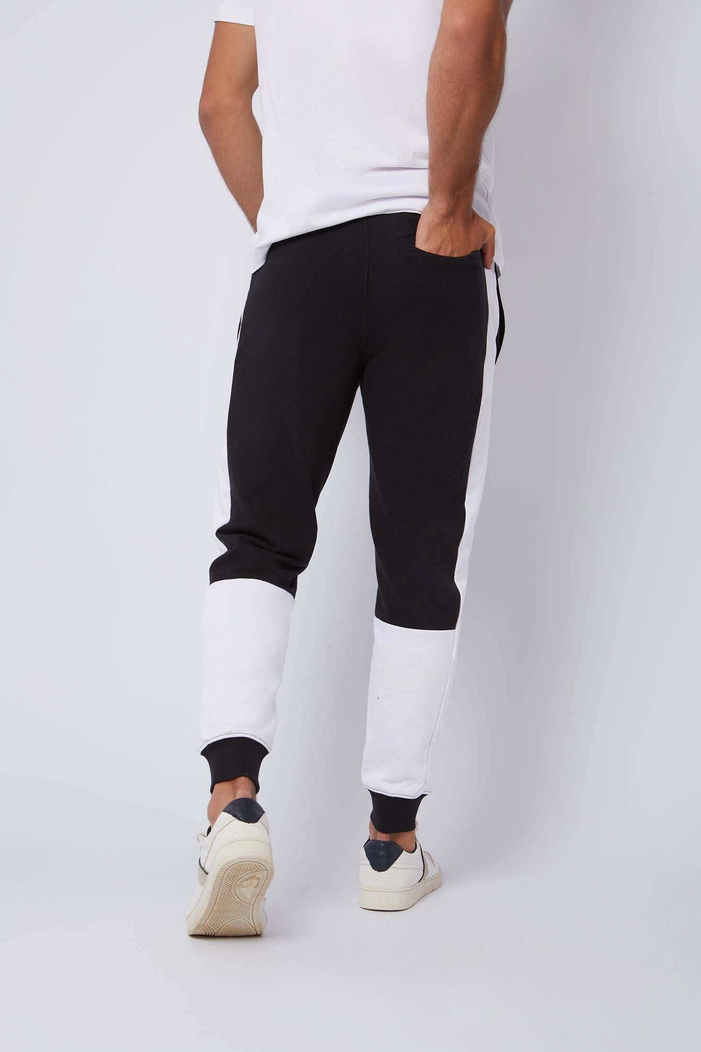 Man wearing black and white colorblock joggers and white sneakers, rear view