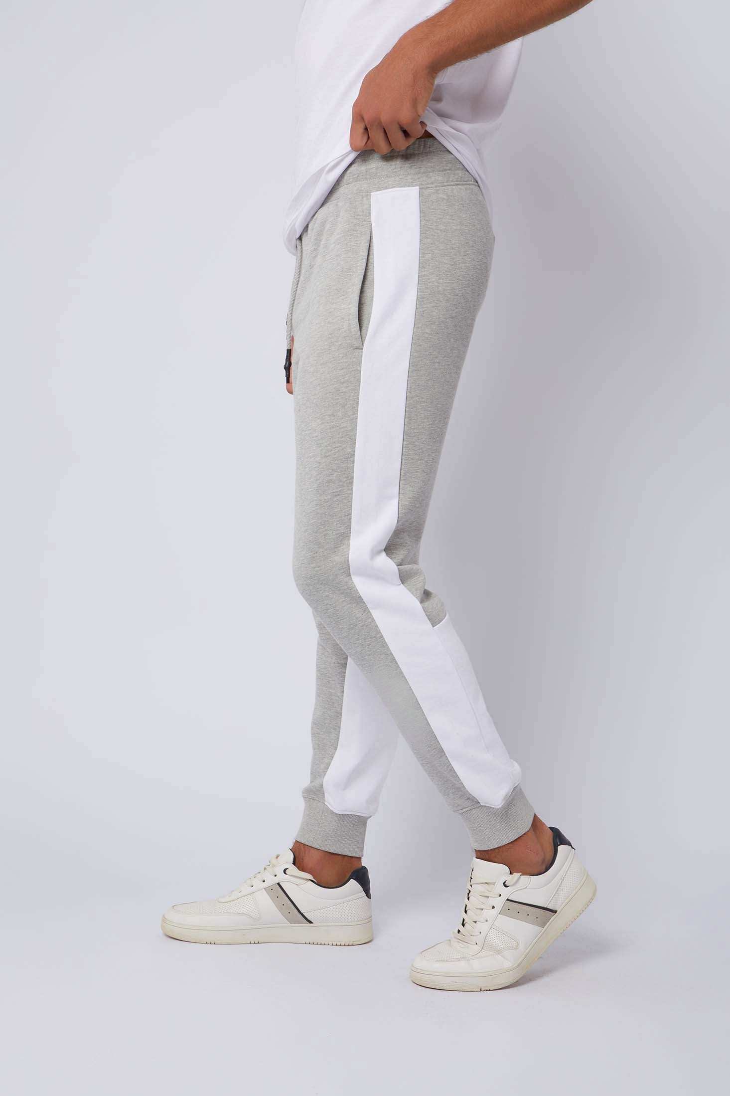 Men's grey jogger pants with white side stripes, casual style, side pockets, paired with white sneakers