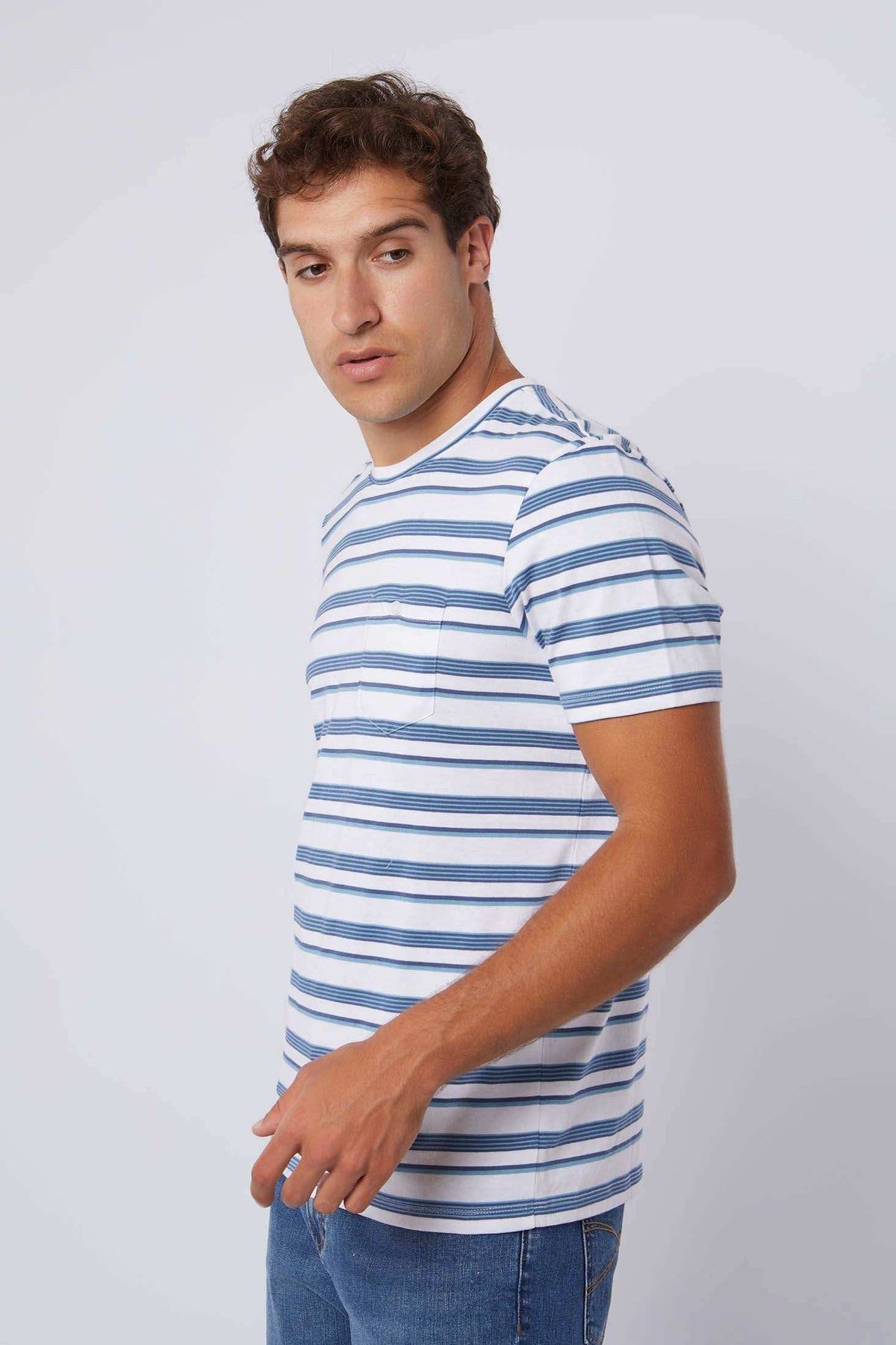 Man wearing a blue and white striped short-sleeve t-shirt and denim jeans