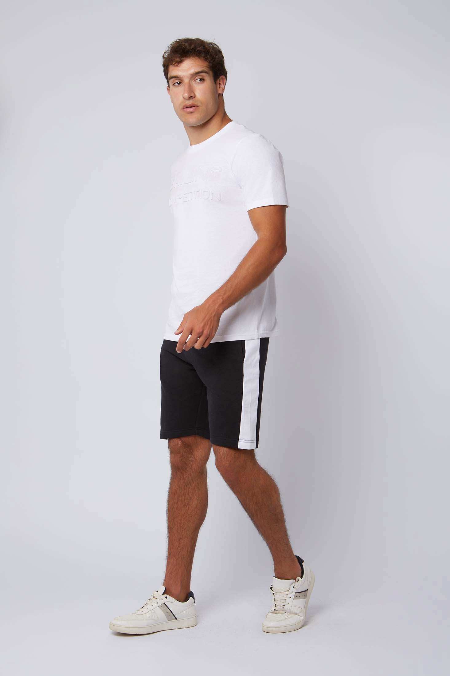 Man in casual white t-shirt, black shorts with white side stripe, and white sneakers
