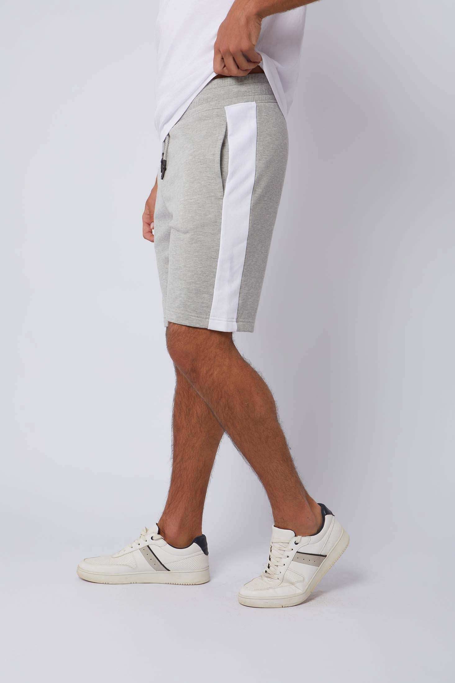Man wearing light grey athletic shorts with white side stripe and white sneakers