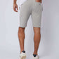 Back view of man in grey athletic shorts with white side stripes and white sneakers