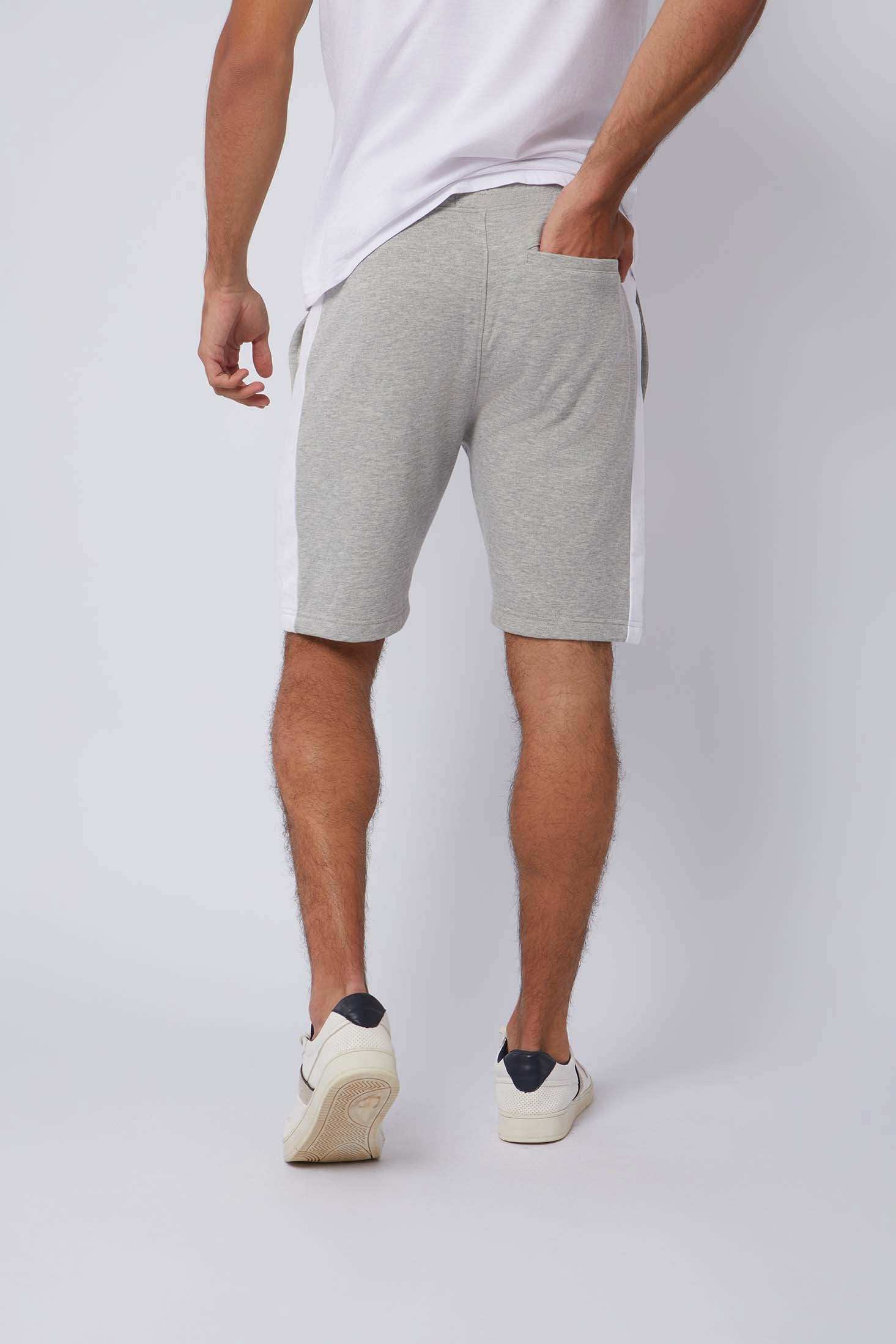 Back view of man in grey athletic shorts with white side stripes and white sneakers
