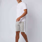 Man wearing white t-shirt, gray athletic shorts and sneakers on plain background