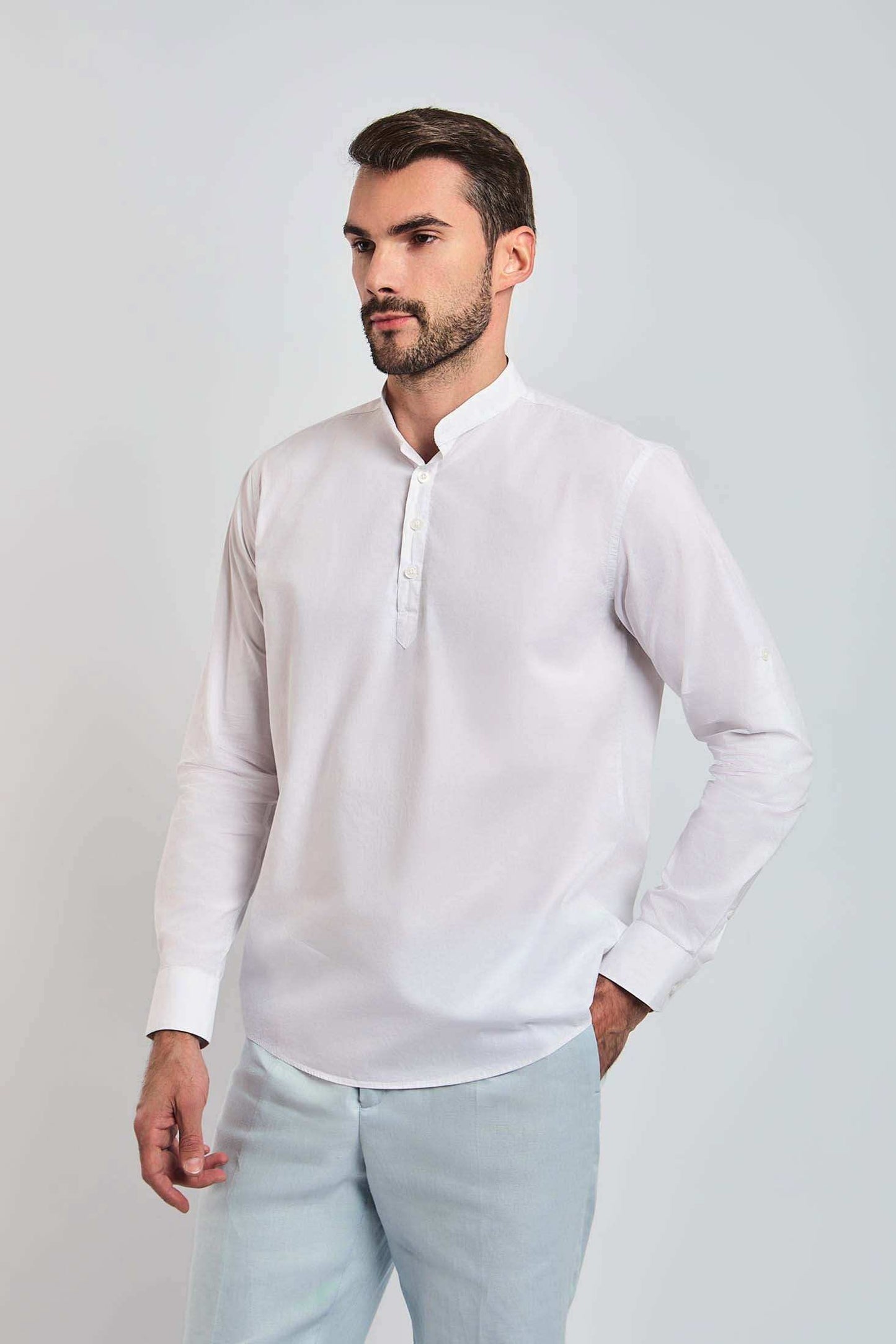 Man wearing a white mandarin collar long sleeve shirt and light pants, casual menswear