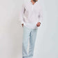 Man wearing white mandarin collar shirt with light blue trousers and brown sneakers