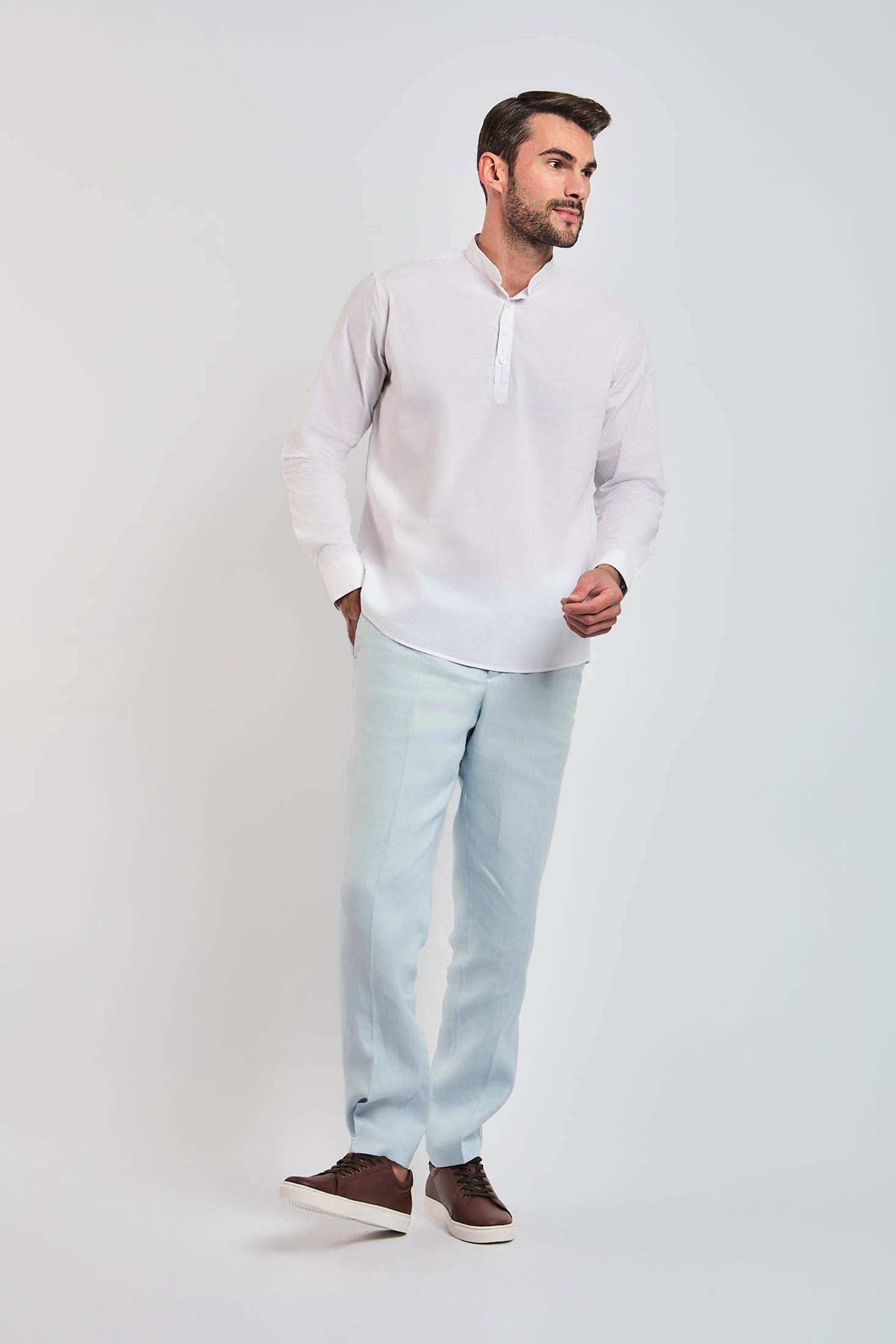 Man wearing white mandarin collar shirt with light blue trousers and brown sneakers
