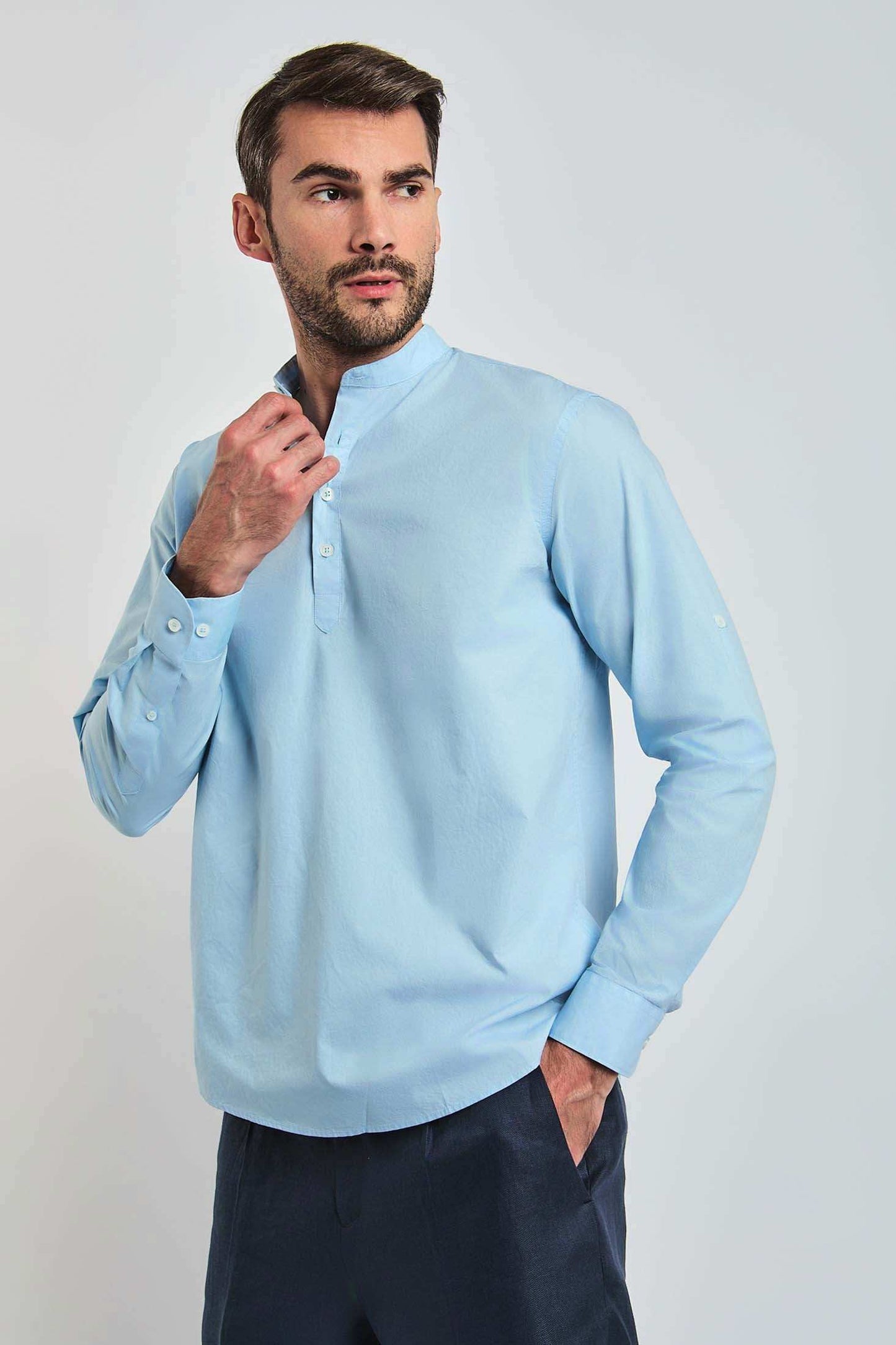 Man wearing a light blue mandarin collar long sleeve shirt with black trousers