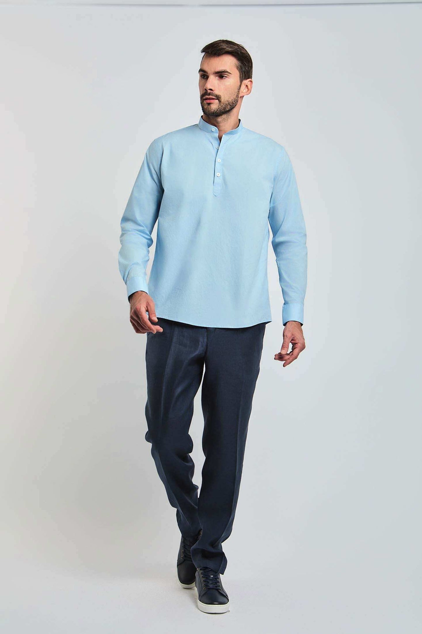 Man wearing a light blue mandarin collar shirt and dark trousers, casual fashion look