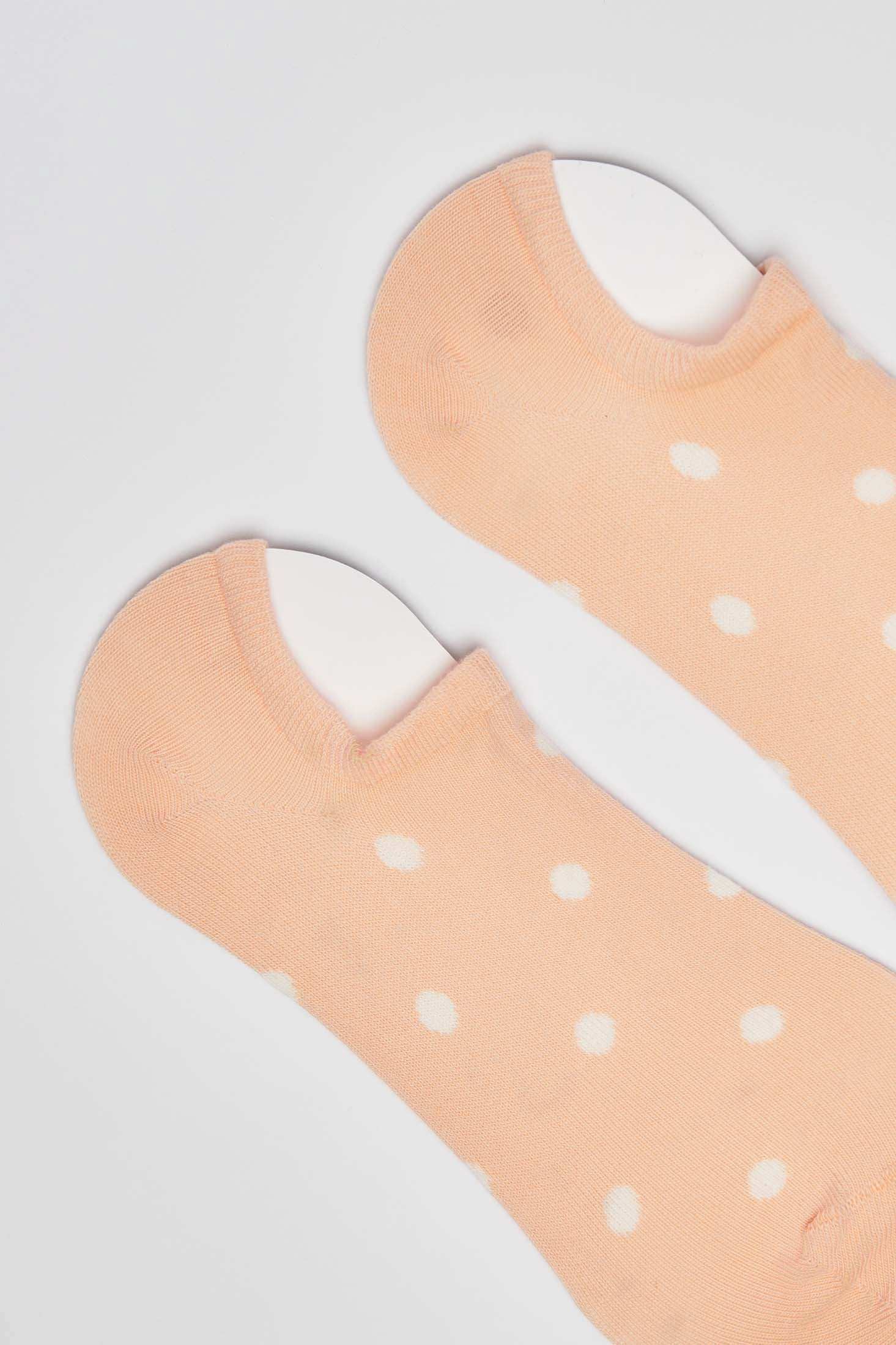 Peach low-cut socks with white polka dots on a plain background