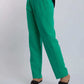 Woman wearing bright green tailored pants and black heeled sandals on white background