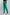 Woman wearing bright green tailored pants and black heeled sandals on white background