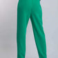 Woman wearing high-waisted green trousers and black heels, rear view