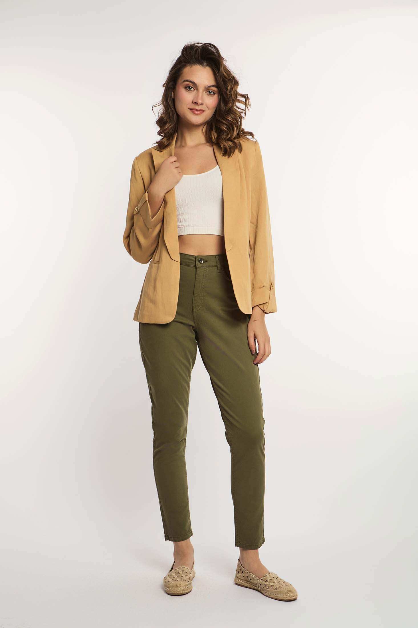 Woman wearing beige blazer, white crop top, olive green pants, and woven loafers