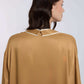 Woman wearing a satin camel blouse with white-trimmed collar, shown from the back