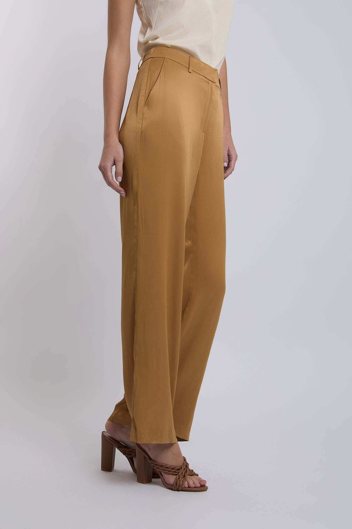 Woman wearing mustard wide-leg trousers with side pockets and tan heeled sandals