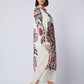 Woman wearing long white dress with vibrant multicolor floral patterns and beige heels