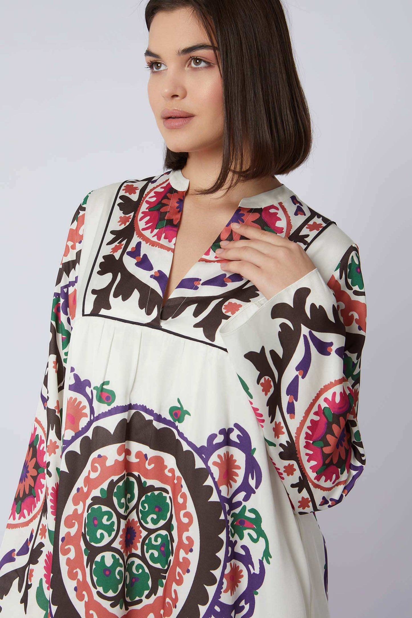 Woman wearing a white dress with colorful, bold geometric and floral patterns