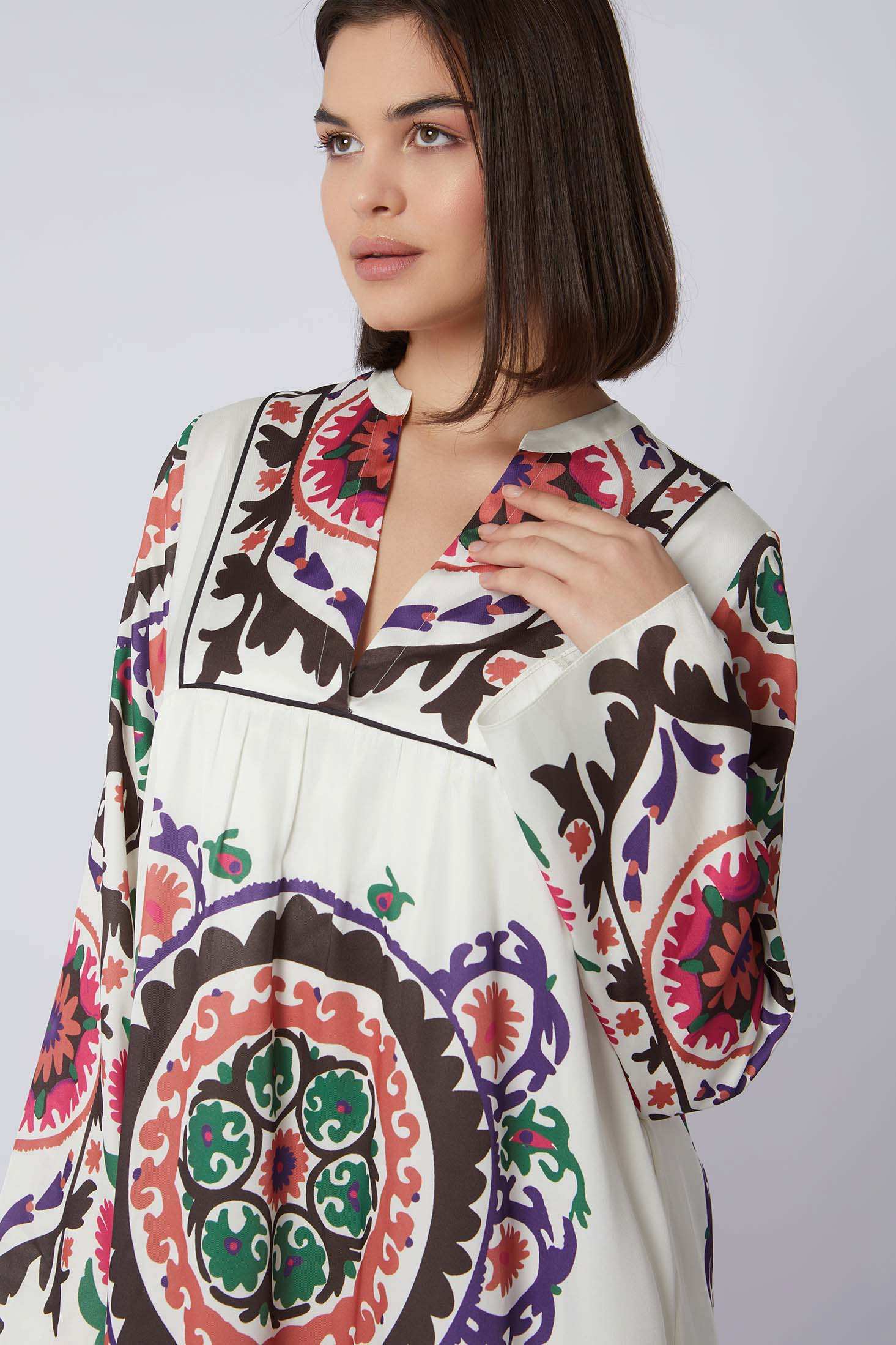Woman wearing a white dress with colorful, bold geometric and floral patterns