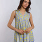 Woman wearing a sleeveless yellow and blue patterned V-neck top with blue pants