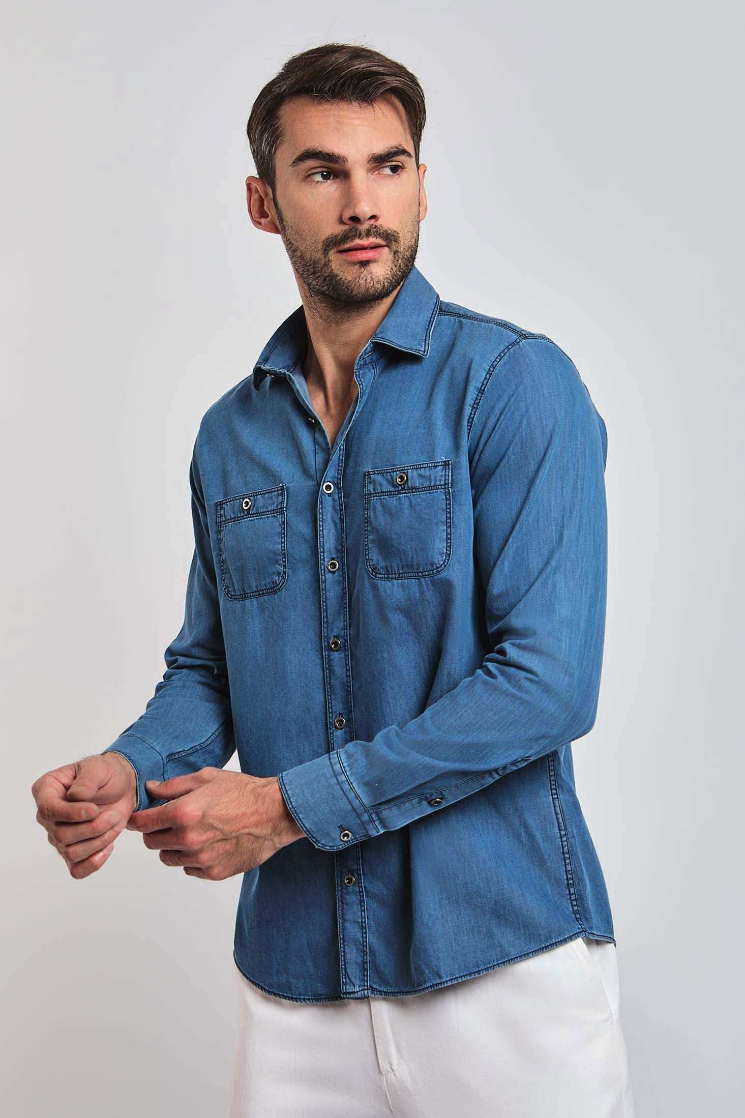 Man wearing a casual blue denim button-up shirt with chest pockets and white pants