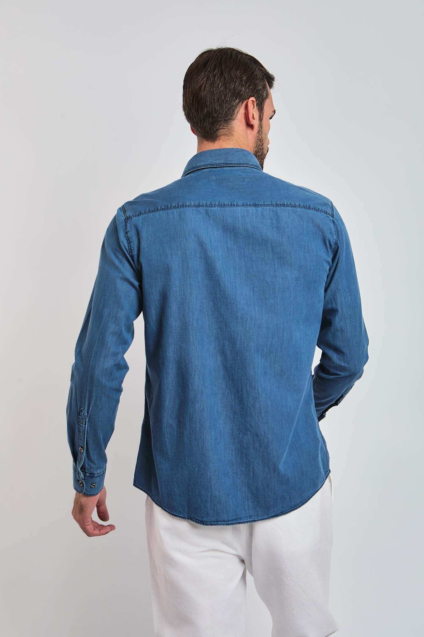 Man in blue denim long sleeve shirt and white pants, back view, casual fashion