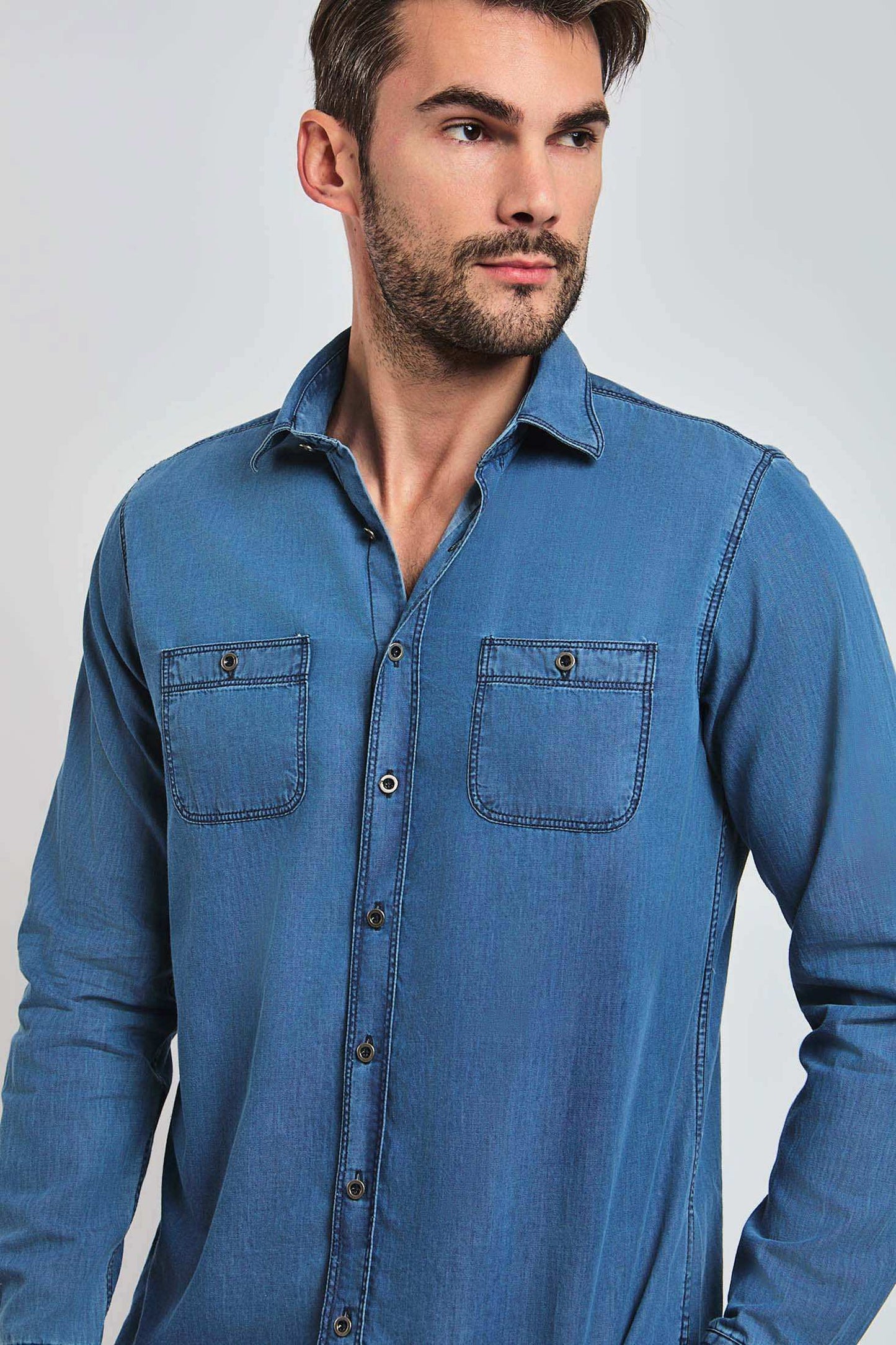 Man wearing a blue denim long-sleeve shirt with button front and chest pockets
