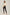 Woman wearing cream high neck blouse, black slim pants, and nude heels on neutral background