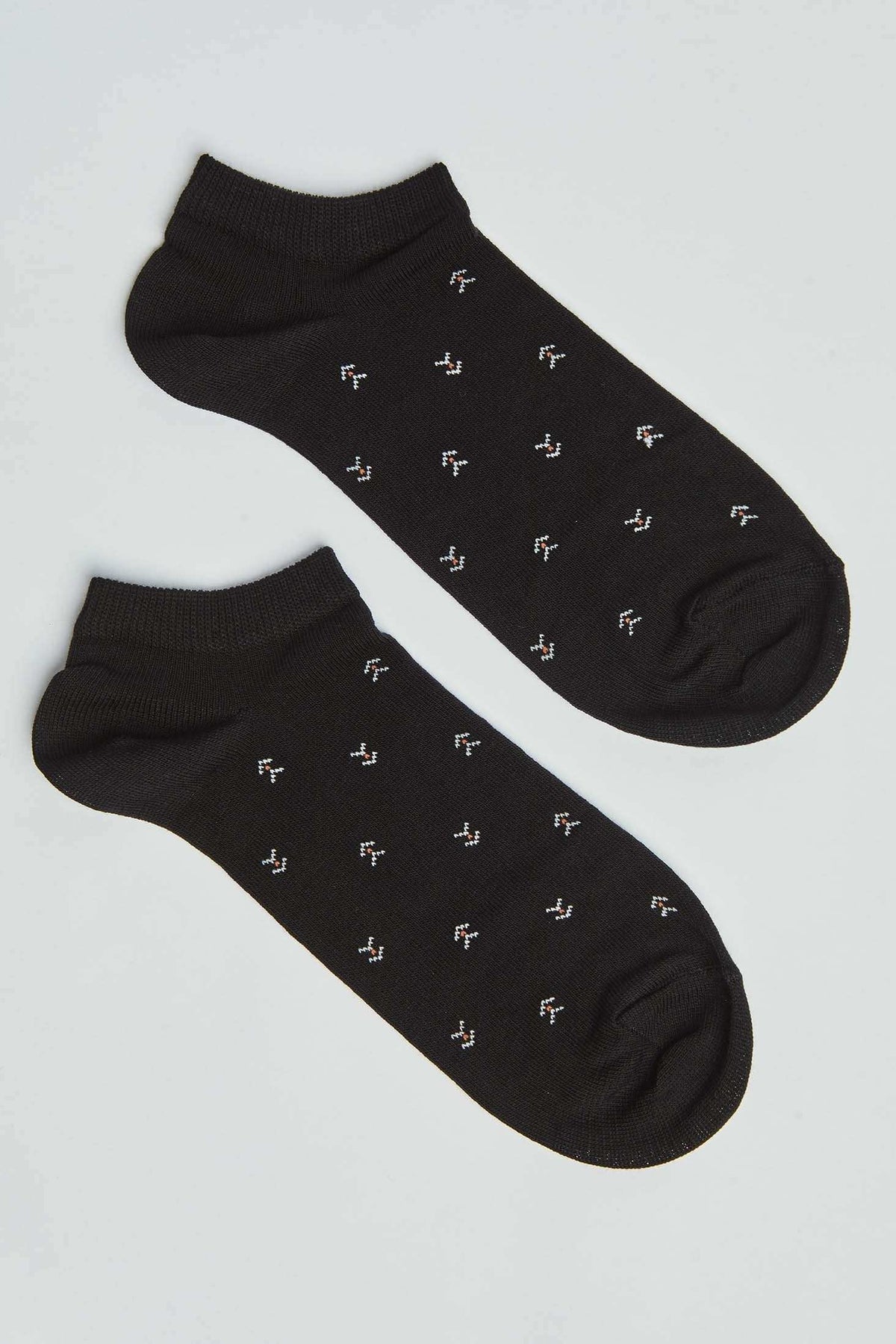 Black ankle socks with small white and red geometric dot pattern on plain background