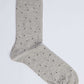 Grey dress sock with small black and white polka dots on a plain background
