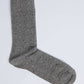 Gray dress sock with small black and white polka dots on a plain background