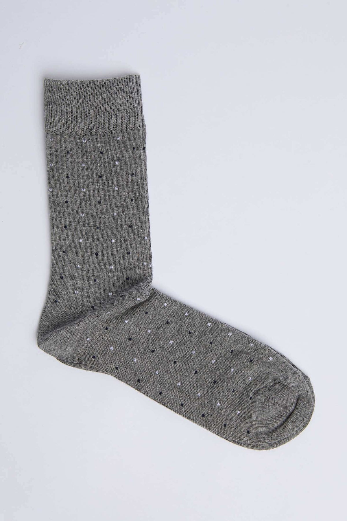 Gray dress sock with small black and white polka dots on a plain background