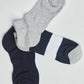 Set of three pairs of socks in grey, navy, and navy with a white stripe on a plain background